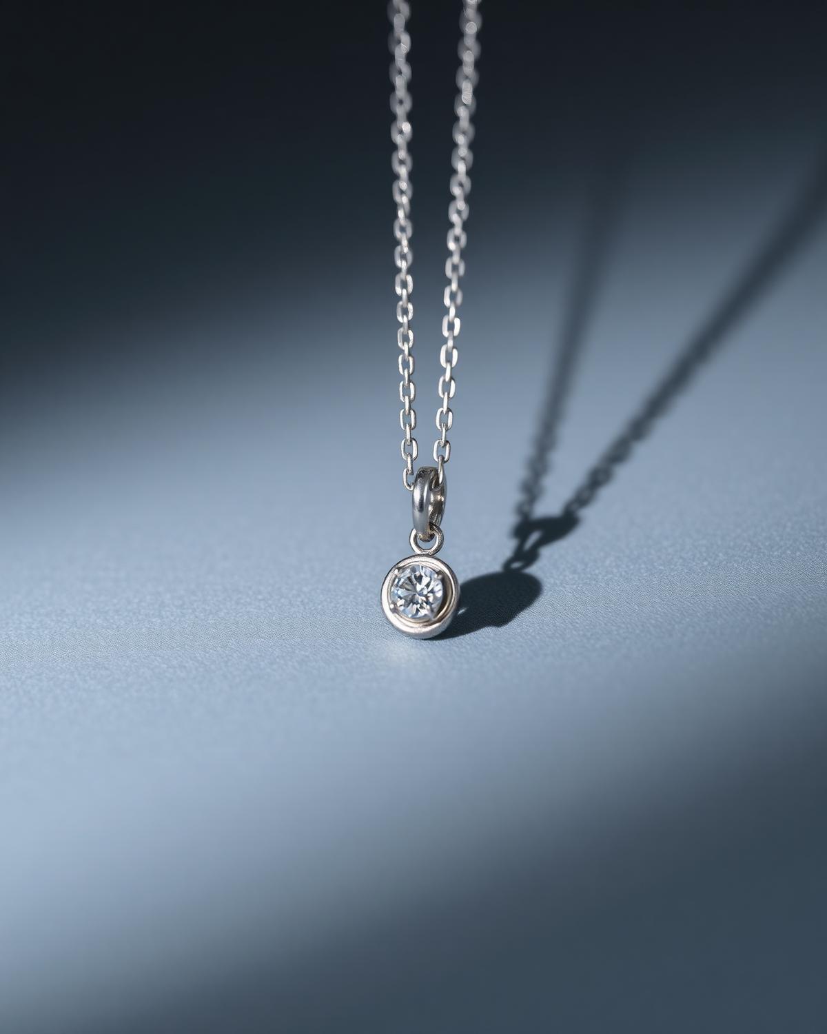 Slim pendant with a single stone on a cool grey ground